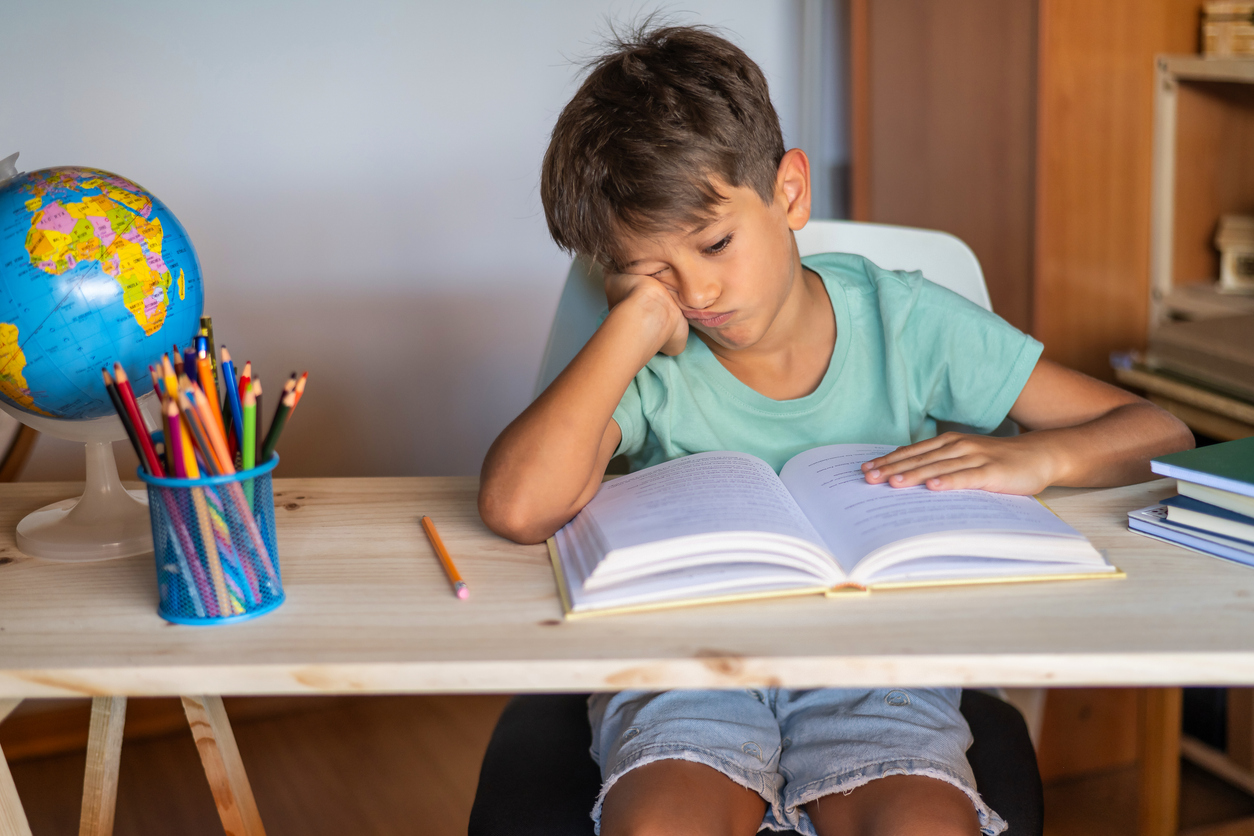 Elementary Boy showing Tired Gesture While Studying.